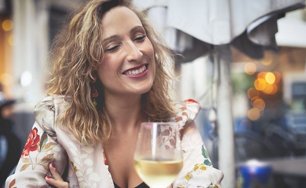 A single older woman drinking white wine