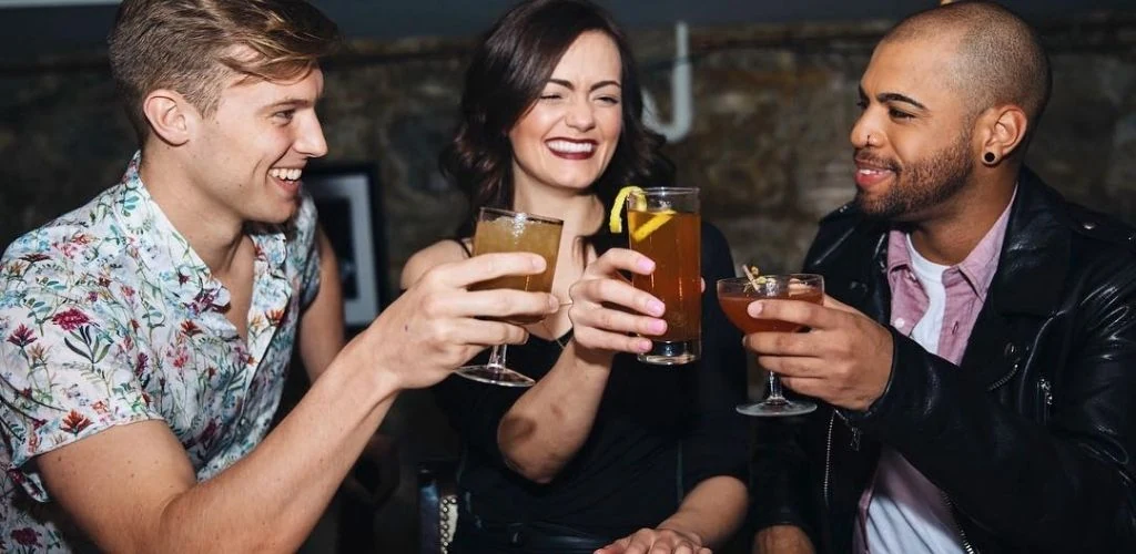 A Kansas City cougar holding drinks with two guys at Manifesto