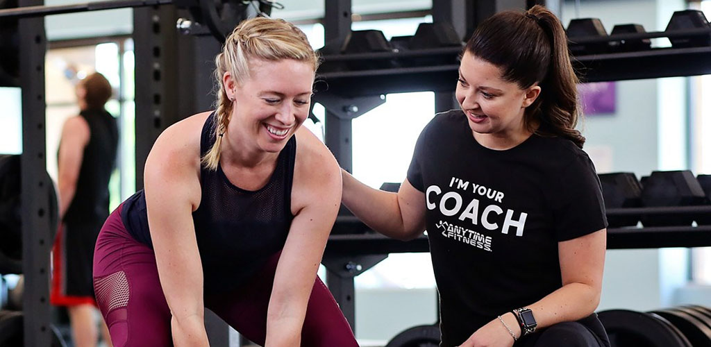 A mature woman working out with a trainer at Anytime Fitness