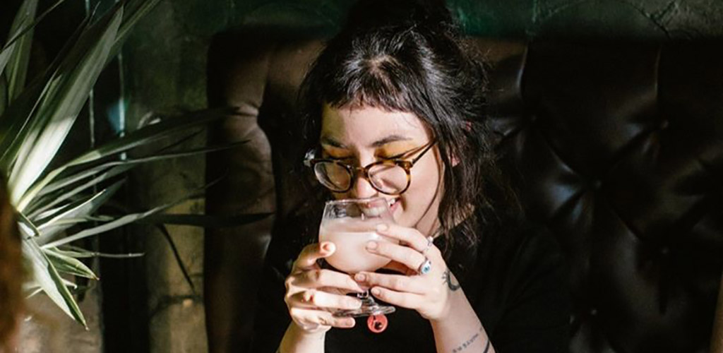 A woman enjoying a cocktail from Dillinger's Cocktails and Kitchen