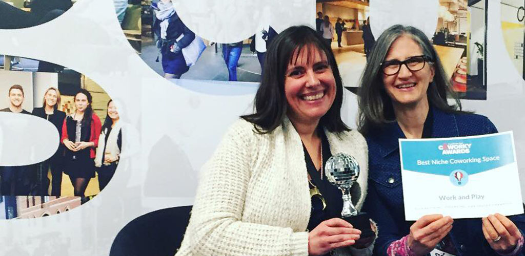 Two women holding awards won by Work and Play