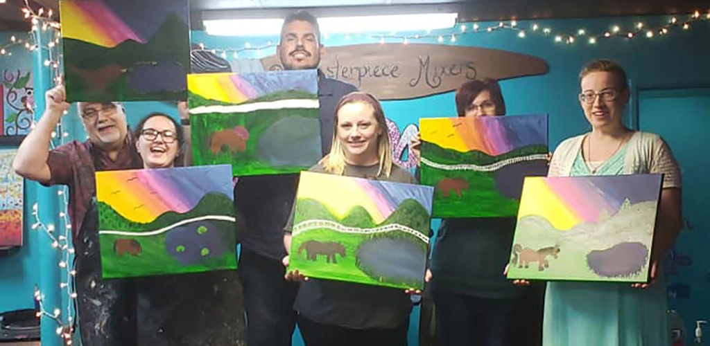 Friends showing off their paintings at Masterpiece Mixers