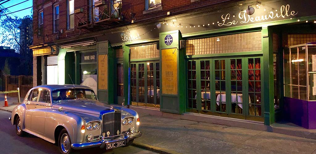 Le Deauville at night with a vintage car parked out front