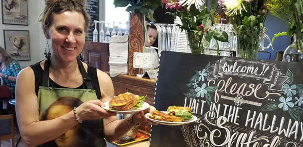 A woman serving sandwiches at Cafe d’ Marie