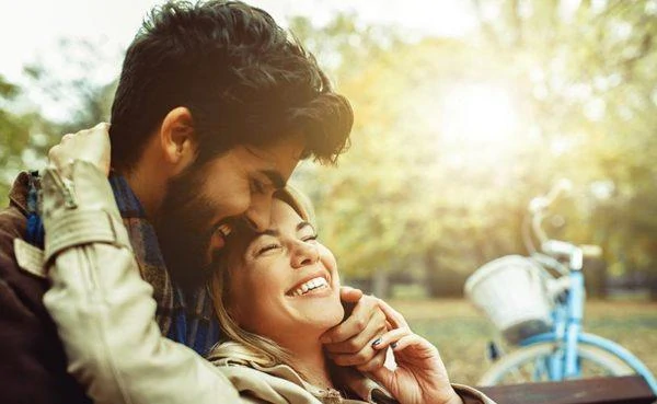 Handsome man learning how to cuddle a girl as she smiles at him