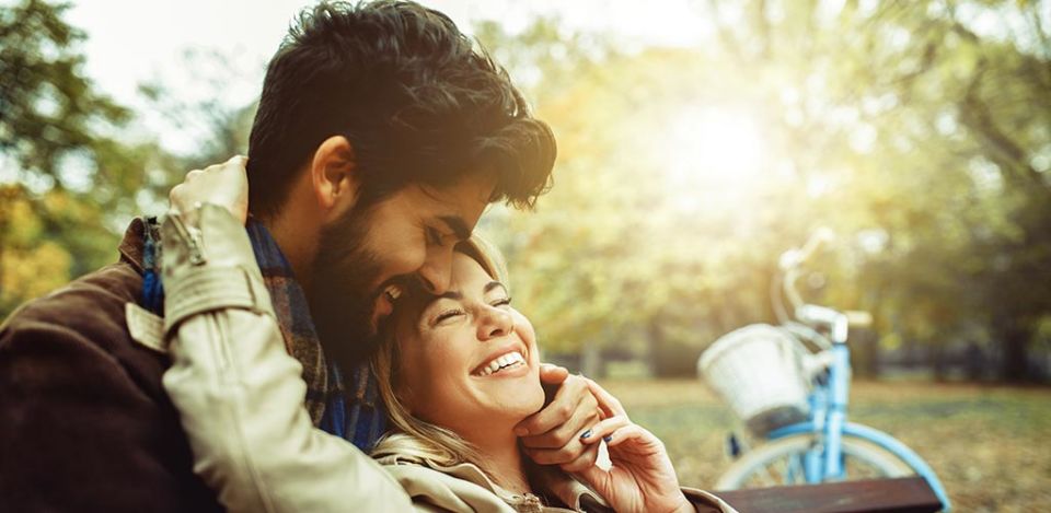 Handsome man learning how to cuddle a girl as she smiles at him