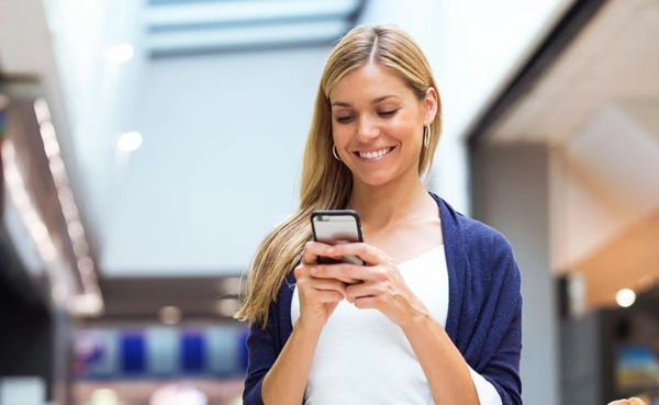 Blonde woman using a Denver dating app at the mall