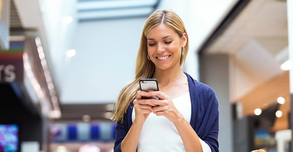 Blonde woman using a Denver dating app at the mall