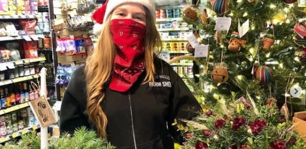 A Reno cute woman holding christmass trees Great Basin Community Food Coop