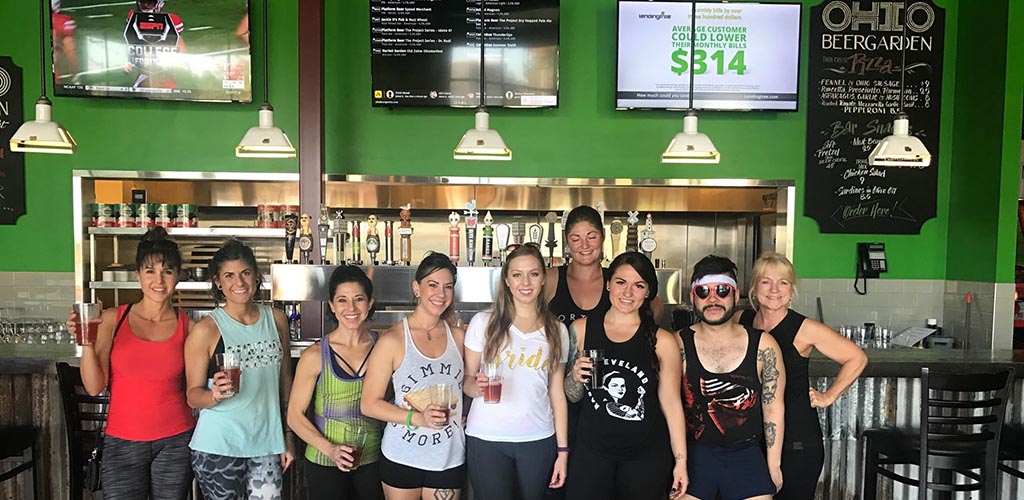 Smiling group of young people hanging out at Ohio Beergarden with beers in hand