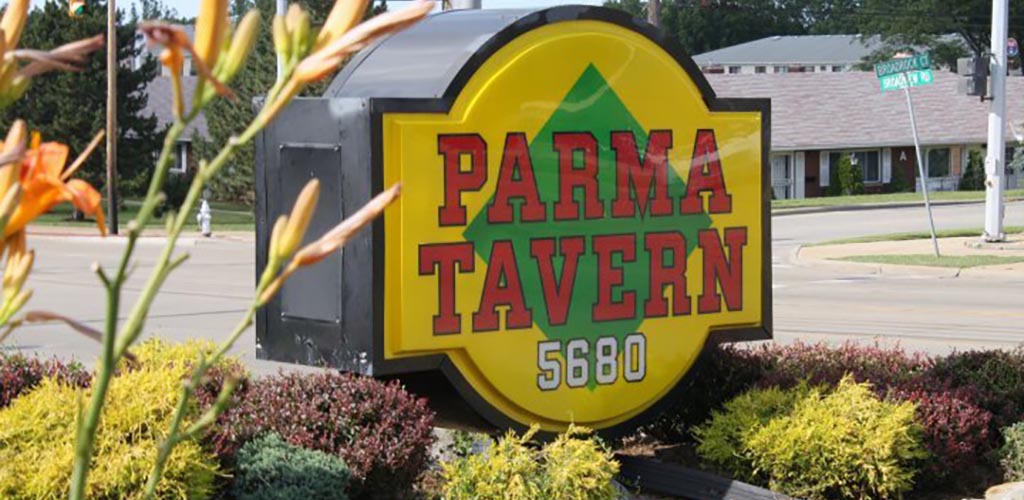 Big yellow subway-shaped sign with green diamond in center and Parma Tavern written in capitals in red centered over top