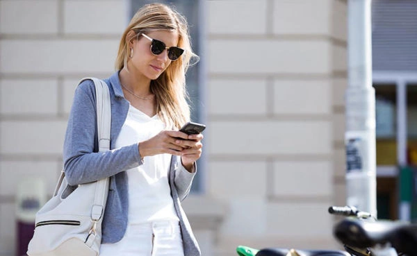 Beautiful young businesswoman texting with her mobile phone whil