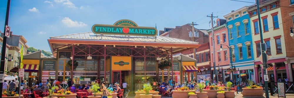 Outdoor setting of Findlay Market with small crowds at tables and lots of potted plants