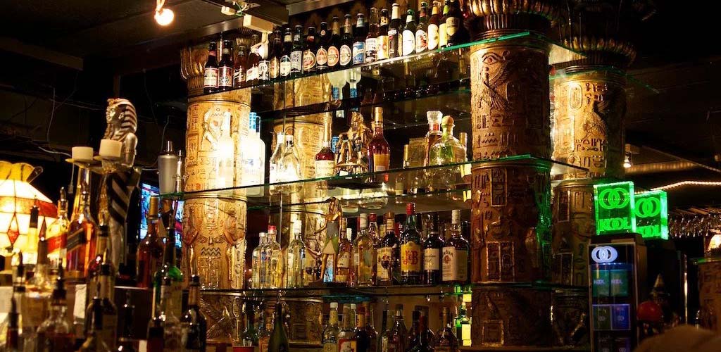 Backlit 3-tier glass bar at The Greenwich showcasing bottles of alcohol