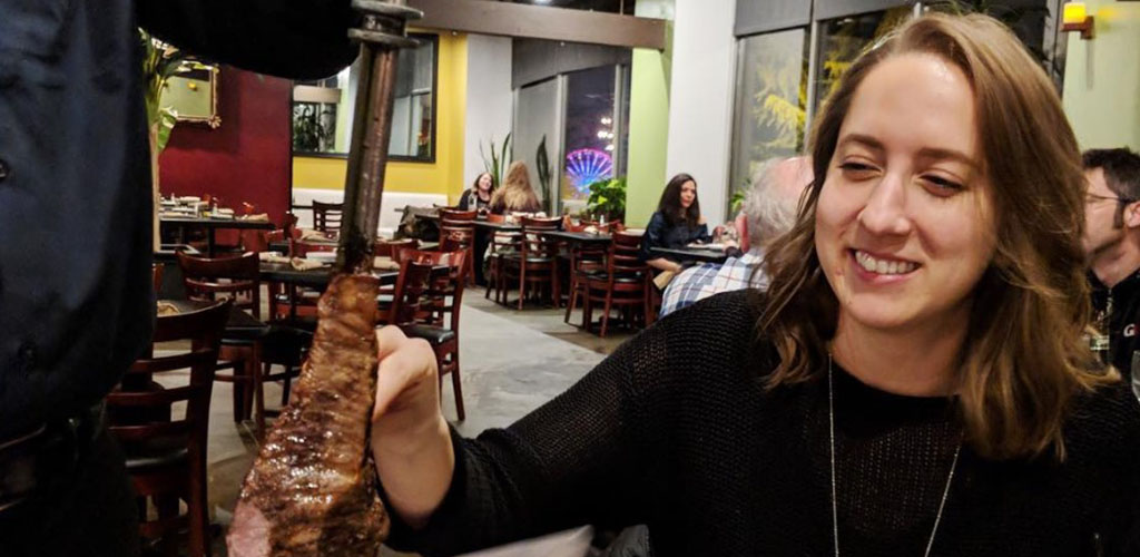 A woman enjoying some Brazilian barbecue from The Grill from Ipanema