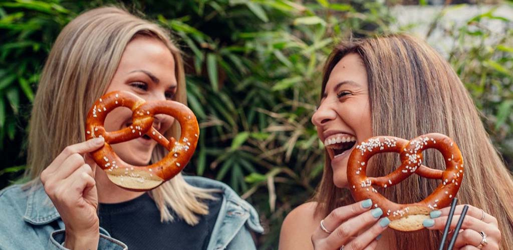 Two cute Gold Coast singles holding pretzels at The Bavarian