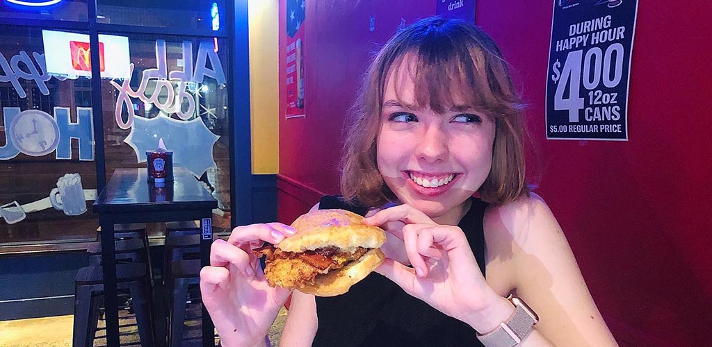 A girl enjoying a big burget at Ben’s Triple B