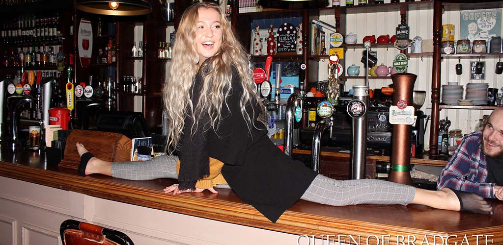 A woman doing the splits on the bar in Queen of Bradgate