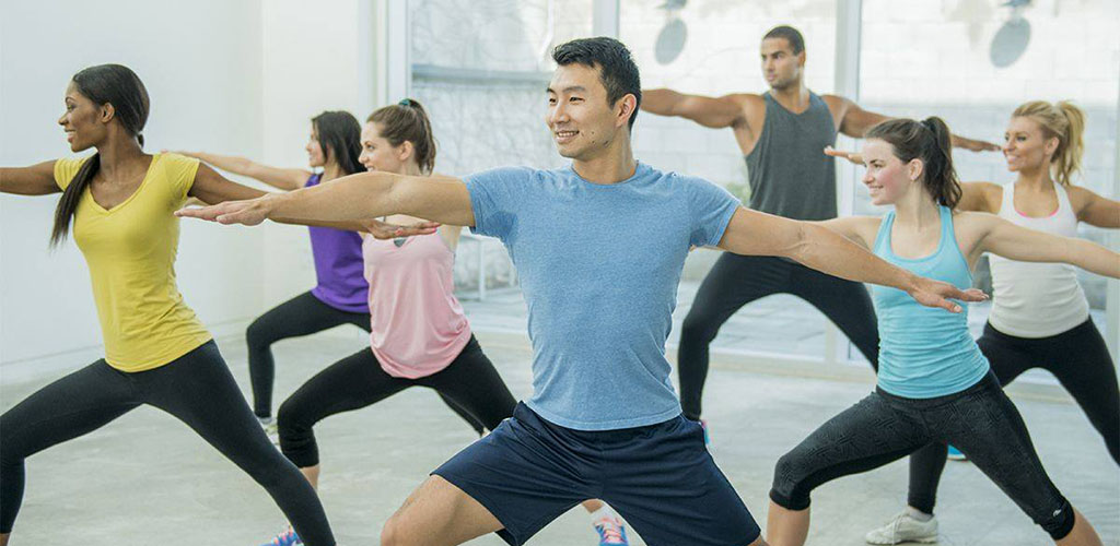 Men and women in a yoga pose at Fitness 1440