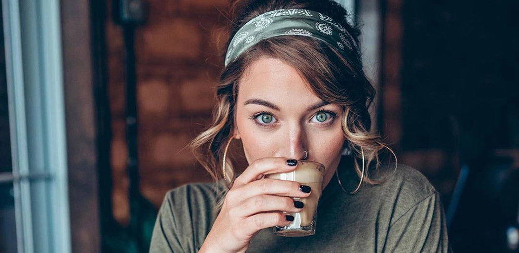 A beautiful girl drinking coffee from Coffee waves