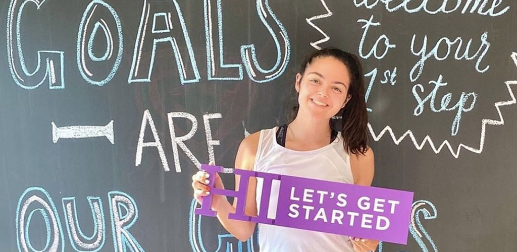 A girl posing in front of a motivational board at Anytime Fitness 