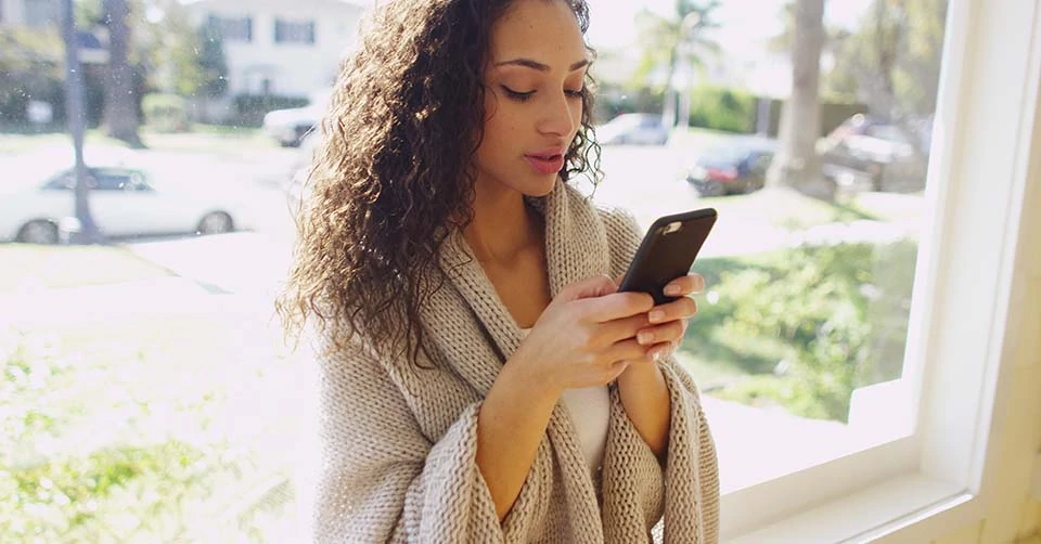 A woman with curly hair trying some Santa Ana dating apps while at home