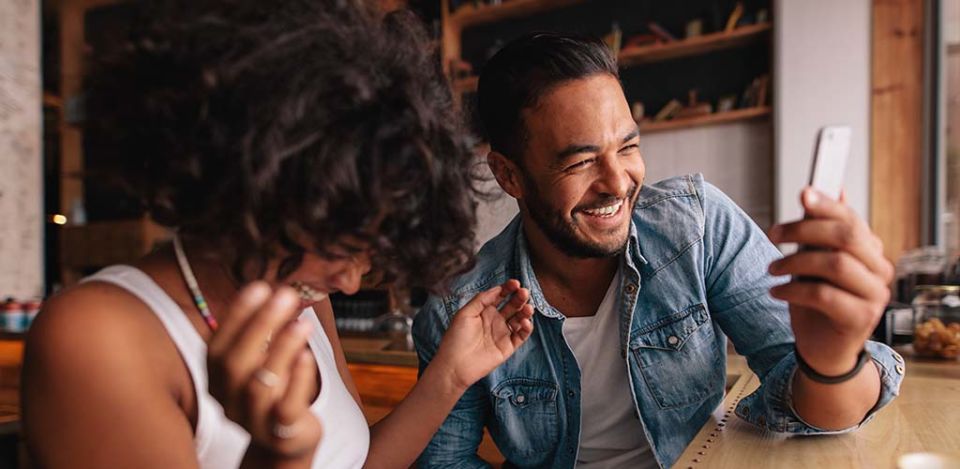 Couple in a cafe laughing about the things to talk about with your crush