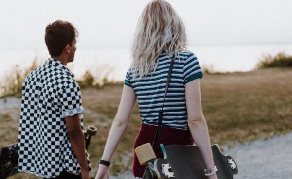 A guy with a skateboard starting a conversation with a girl