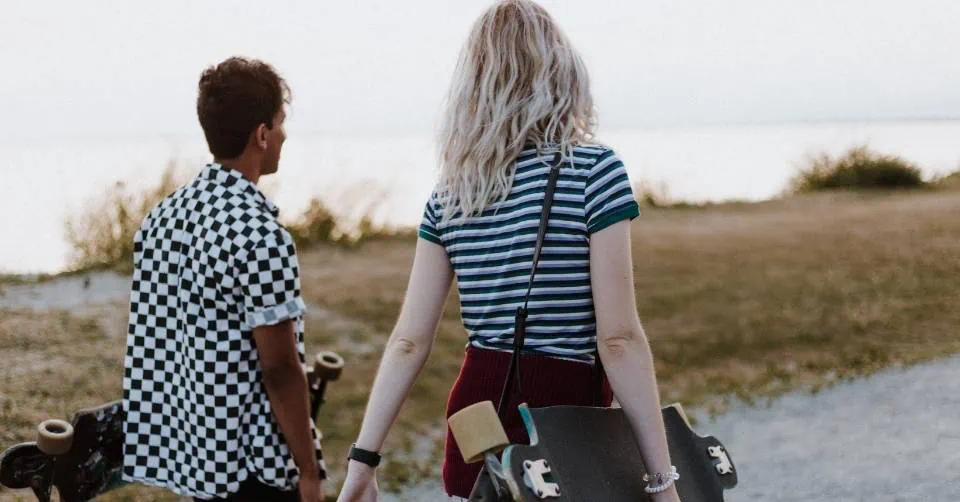 A guy with a skateboard starting a conversation with a girl