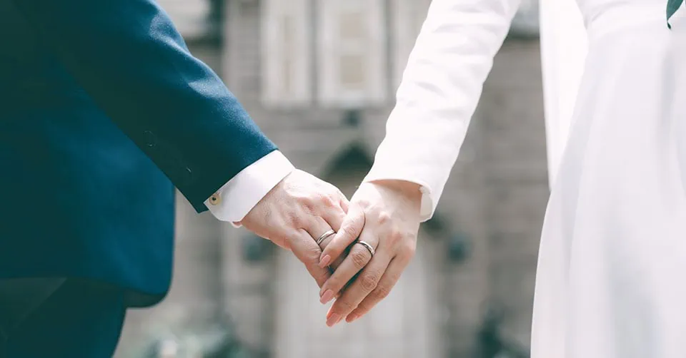 A committed couple wearing wedding rings