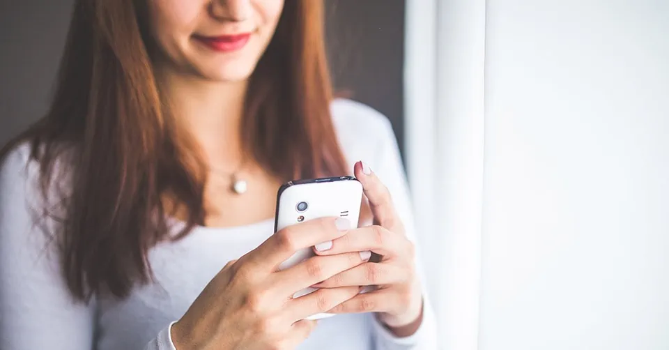 A woman smiling while texting someone