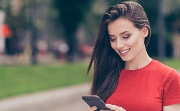 A woman in a red shirt checking out the top New York dating apps