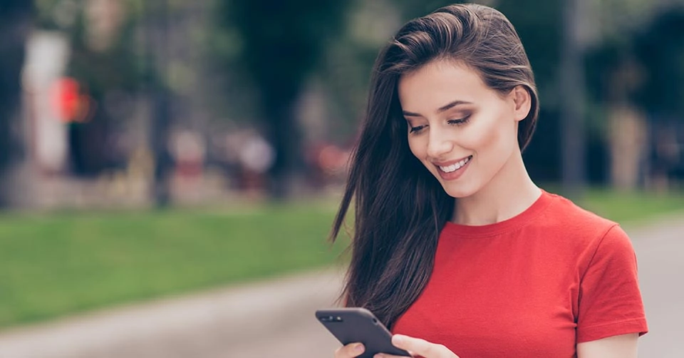 A woman in a red shirt checking out the top New York dating apps