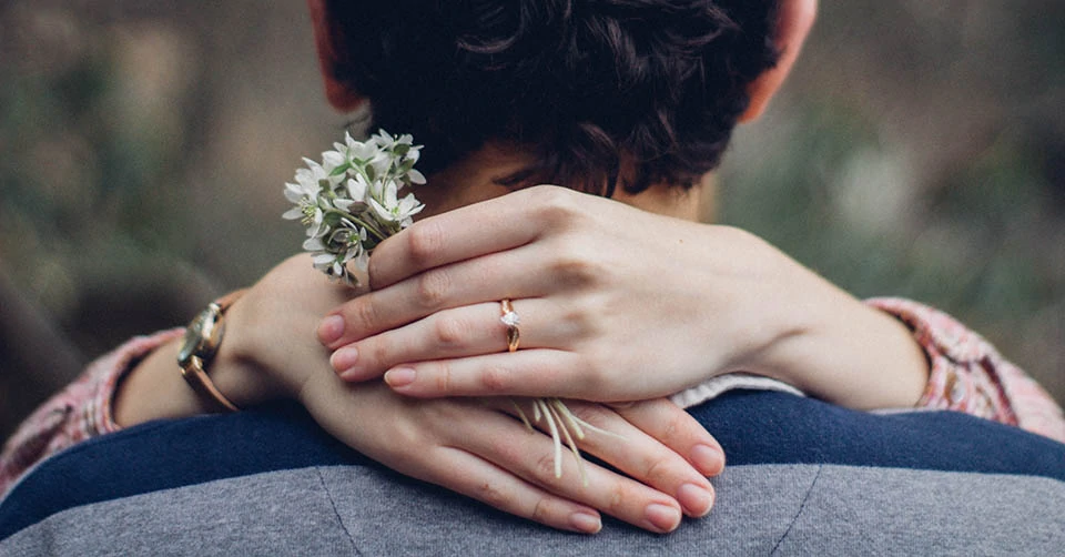 A woman with an engagement ring and a dandelion