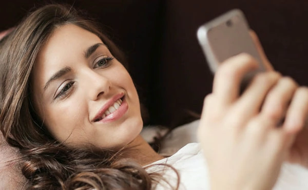 A young woman using Salt Lake City dating apps while lounging on the sofa