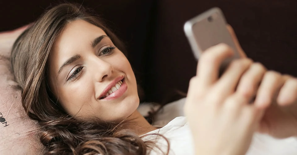 A young woman using Salt Lake City dating apps while lounging on the sofa