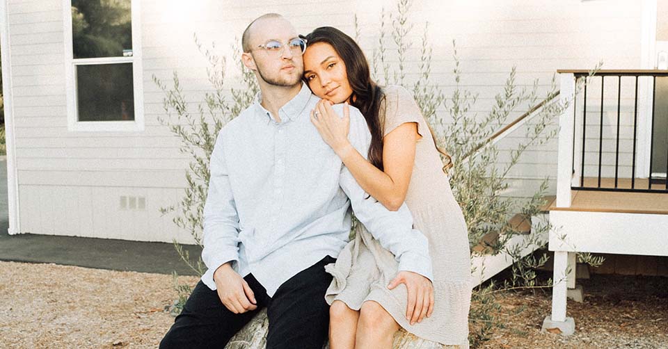 Happily married couple in front of their house