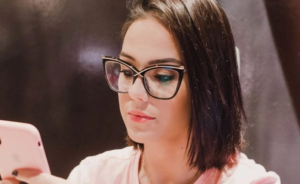 Woman in glasses using a Pennsylvania dating app at a cafe