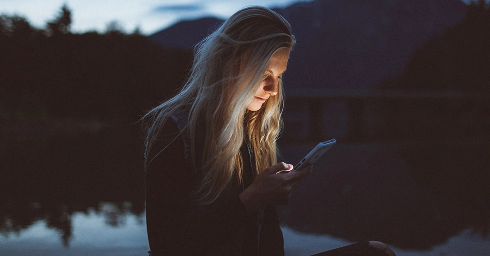 A woman using Washington dating apps while at the lake