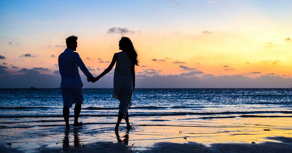 A couple walking in the beach at sunset