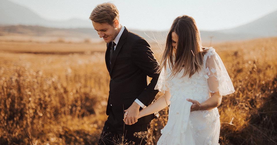 A married couple walking through a field