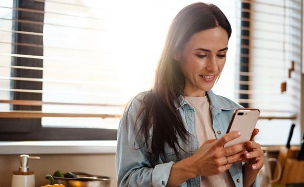 A woman using an Indiana dating app while making dinner