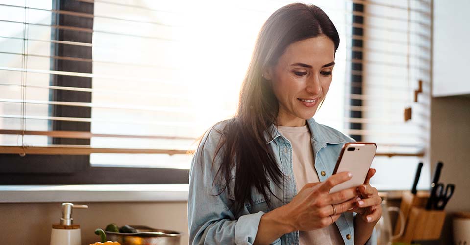 A woman using an Indiana dating app while making dinner