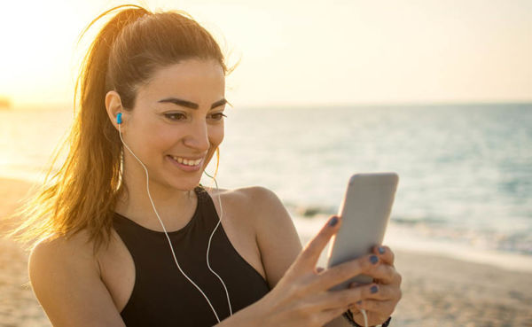 Athletic young woman using a St. Petersburg dating app at the beach