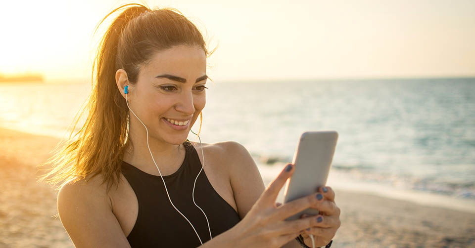 Athletic young woman using a St. Petersburg dating app at the beach