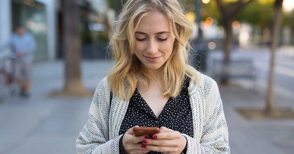 Woman in a cardigan using a Maine dating app to find a date