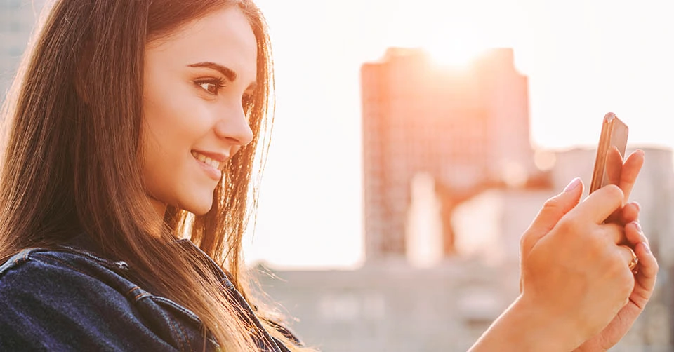 A young woman in a denim jacket trying an Idaho dating app