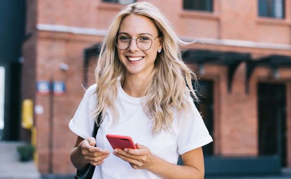 Woman in glasses using a dating app while walking