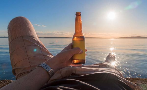 A man enjoying a beer by the sea